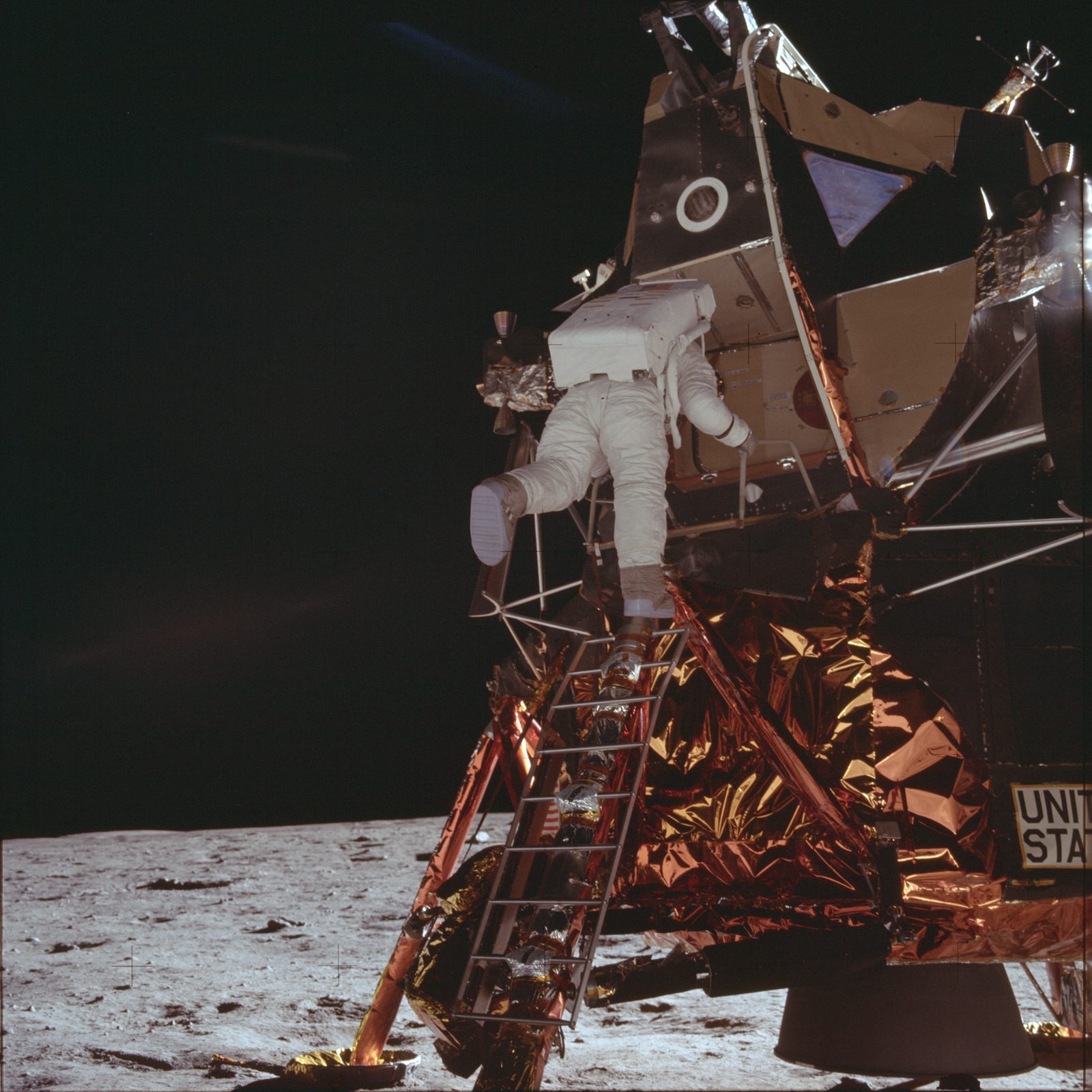 A crewman descending the LM ladder in the full Apollo pressure garment and PLSS backpack; the photography index captions the ladder sequence "Armstrong," but the photographer egressed first, so the descending figure is Aldrin (AS11-40-5866, NASA).