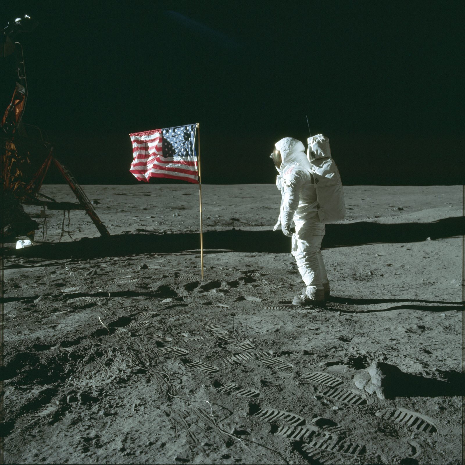 Aldrin standing beside the deployed U.S. flag, the LM Eagle at left (AS11-40-5874, NASA).