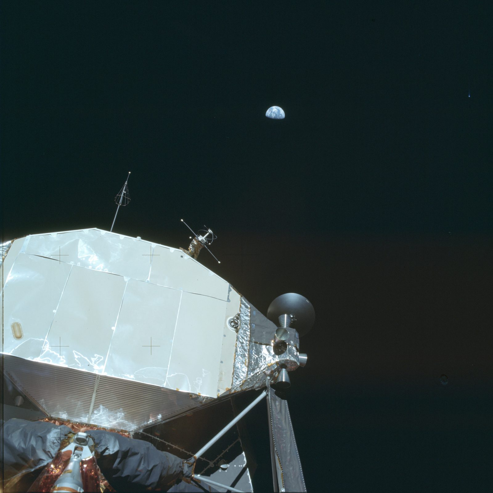 Looking up at the Lunar Module Eagle on the surface, the Earth in the black sky beyond (AS11-40-5923, NASA).