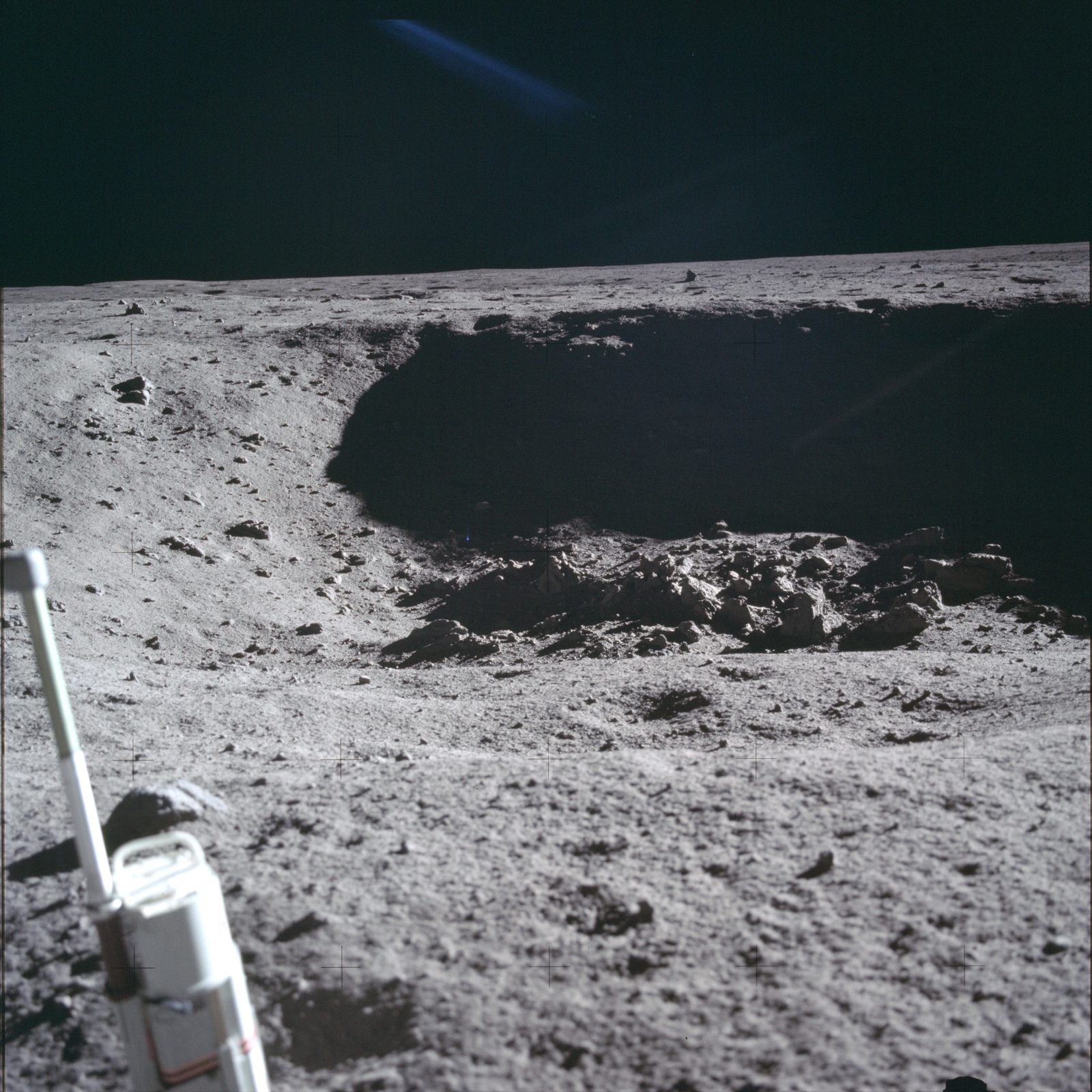 A small crater with a blocky, rocky floor near the LM, photographed during the late-EVA documented-sampling stretch (AS11-40-5954, NASA).